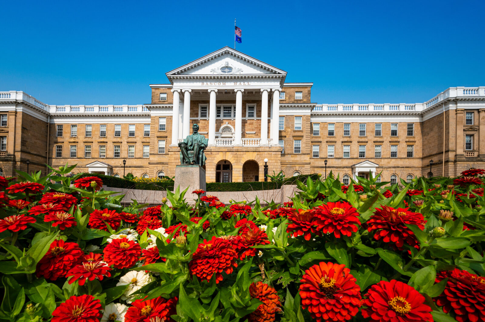 Bascom Hall framed by red and white zinnias in the summer time.